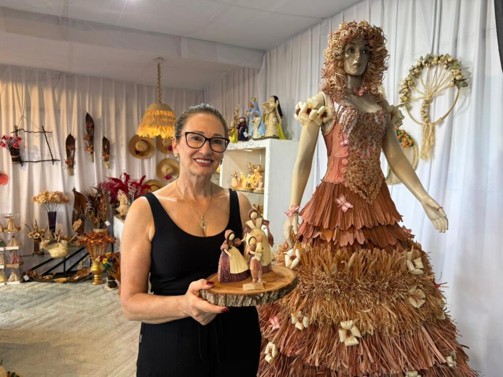 Artesã de Xanxerê ao lado de um manequim com vestido de palha de milho