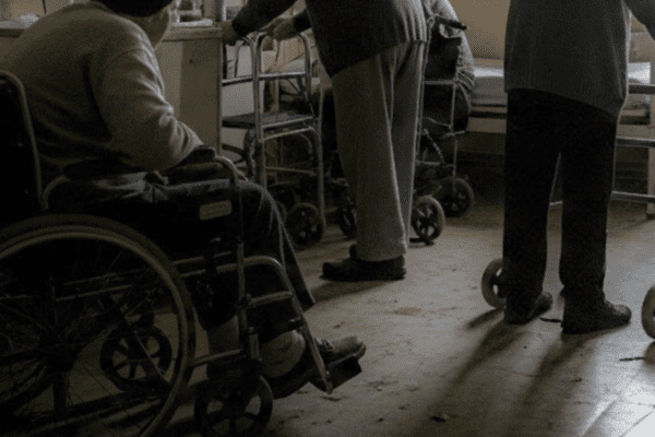 Imagem de idoso em cadeira de rodas em lugar obscuro