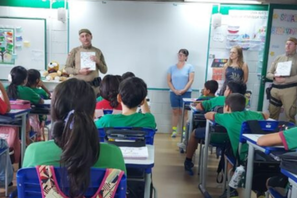 Dois policiais dando as aulas do Proerd para uma sala de aula cheia de alunos em Xanxerê