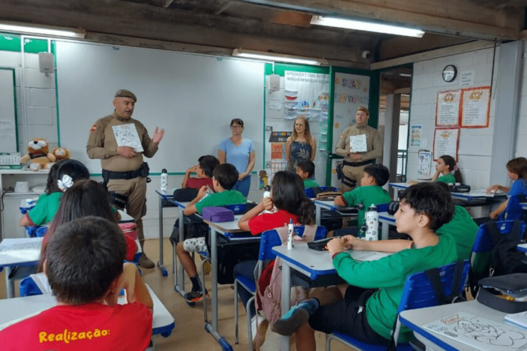 Dois policiais dando as aulas do Proerd para uma sala de aula cheia de alunos em Xanxerê
