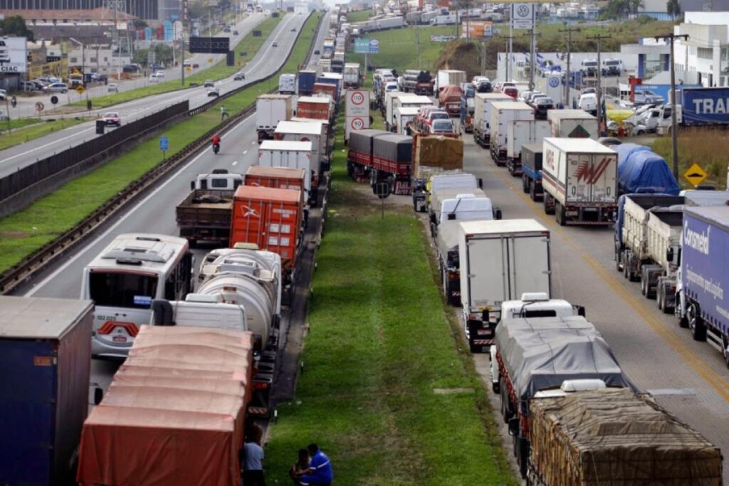 Imagem de rodovia com vários caminhões estacionados na lateral em greve