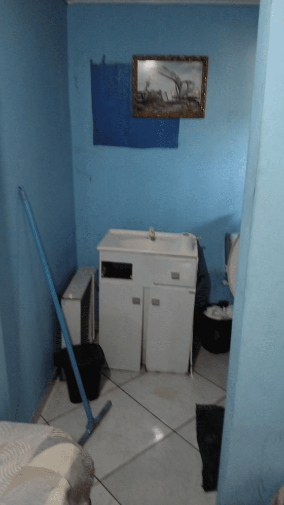 Imagem da pia em más condições de um banheiro com paredes azuis