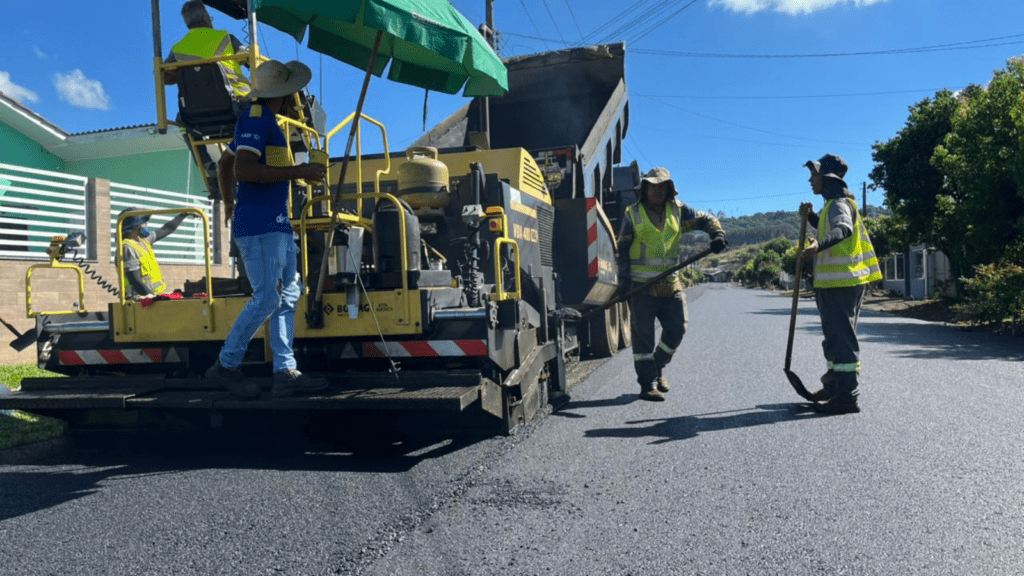 Máquina de asfaltamento com operadores ao redor