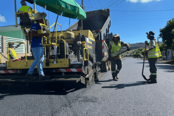 Máquina de asfaltamento com operadores ao redor