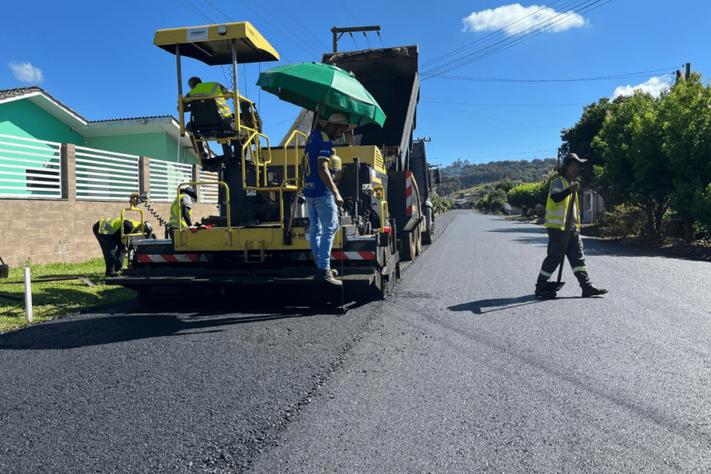 Máquina de asfaltamento com operadores ao redor