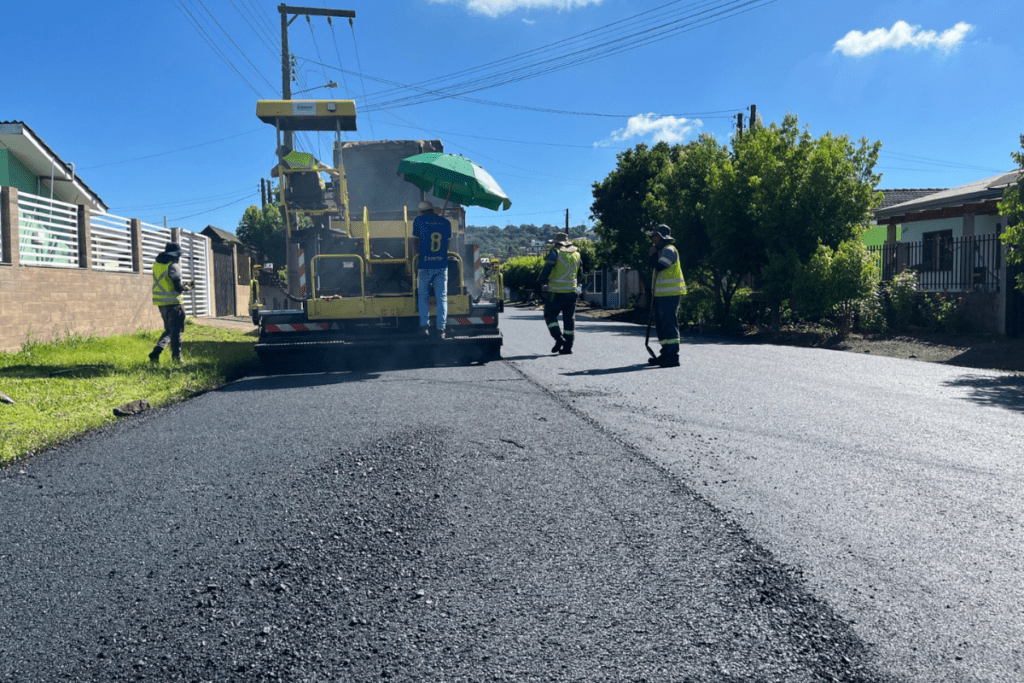 Máquina de asfaltamento com operadores ao redor