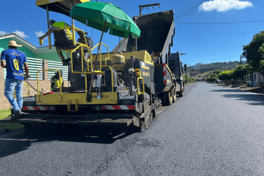 Máquina de asfaltamento com operadores ao redor