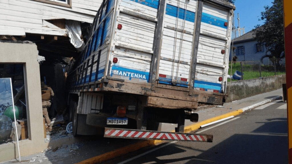 Um caminhão batido e com a cabine dentro de um estabelecimento após acidente