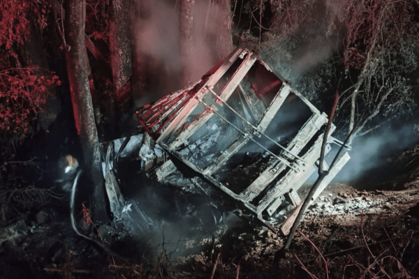 Imagem de caminhonete caída em ribanceira totalmente queimada.