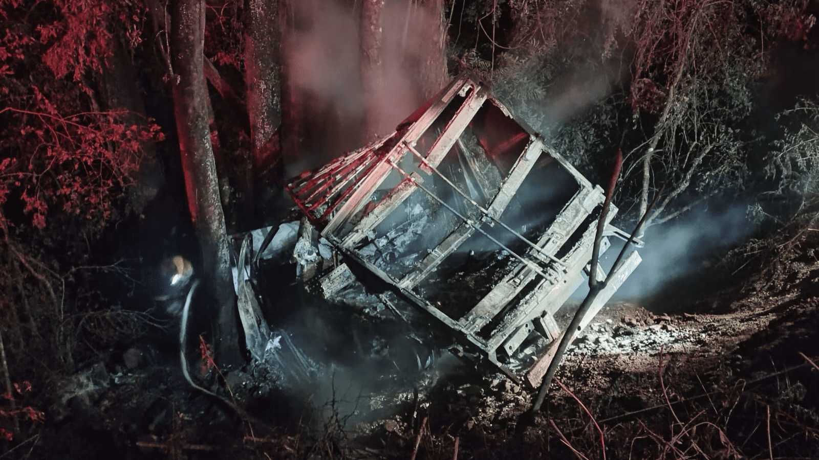 Imagem de caminhonete caída em ribanceira totalmente queimada.