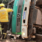 Imagem caminhão tombado com dois bombeiros ao redor
