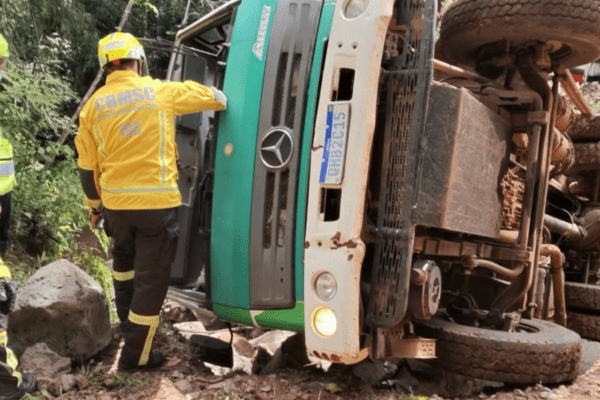 Imagem caminhão tombado com dois bombeiros ao redor