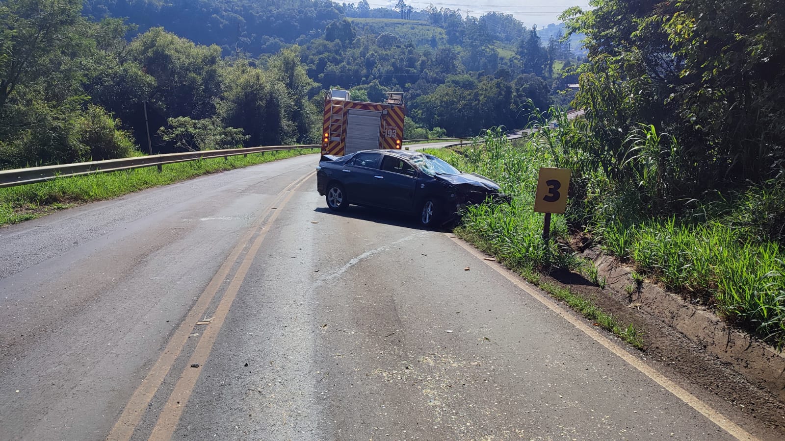 imagem de rodovia com veículo na lateral após capotamento