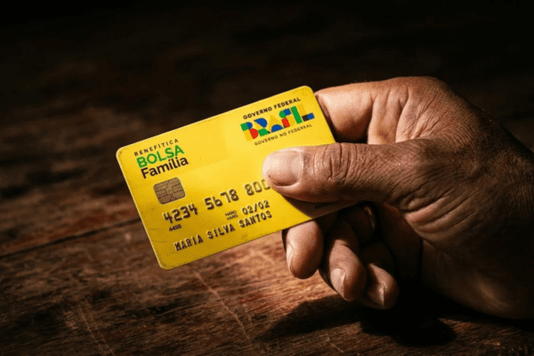 Mão segurando cartão do programa Bolsa Família