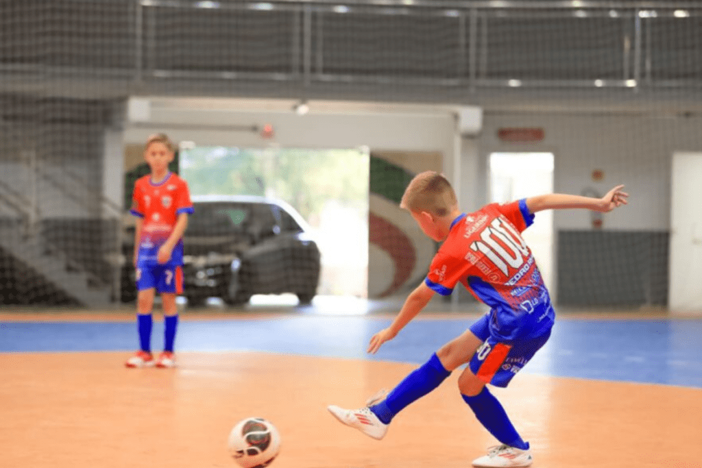 Jogador em quadra chutando a bola na Copa Municipal de Futsal de Xanxerê.