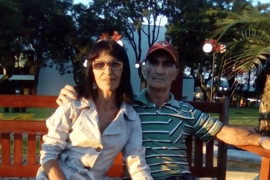 Ana Leda Santoro e Valdir Santoro abraçados e sentados em um banco de praça.