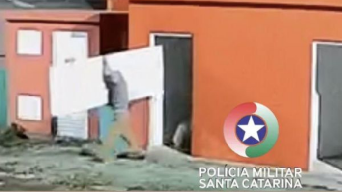 Homem carregando porta de alumínio roubada do Centro Integrado de Saúde de Xanxerê