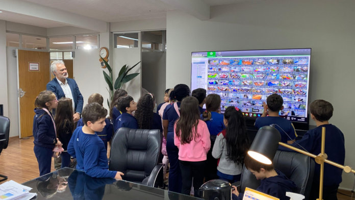 Alunos no gabinete do prefeito de Xanxerê olhando um monitor de câmeras