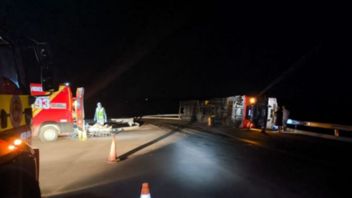 Rodovia com carros dos bombeiros á esquerda e caminhão tombado á direita