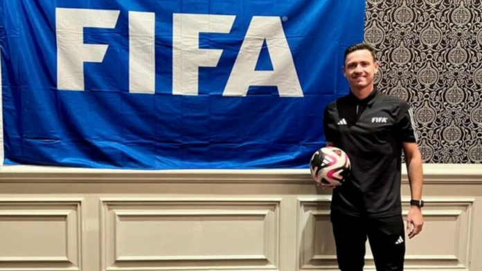 Árbitro catarinense Ramon Abatti Abel ao lado de uma bandeira da FIFA