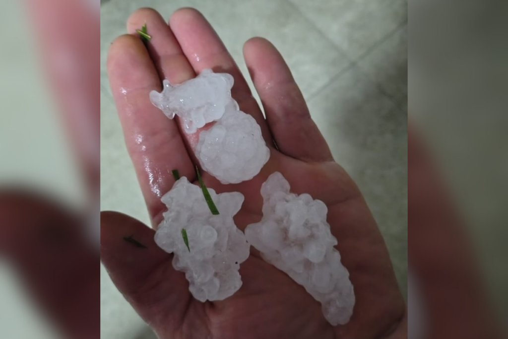 Mão segurando pedra de gelo (granizo) grandes