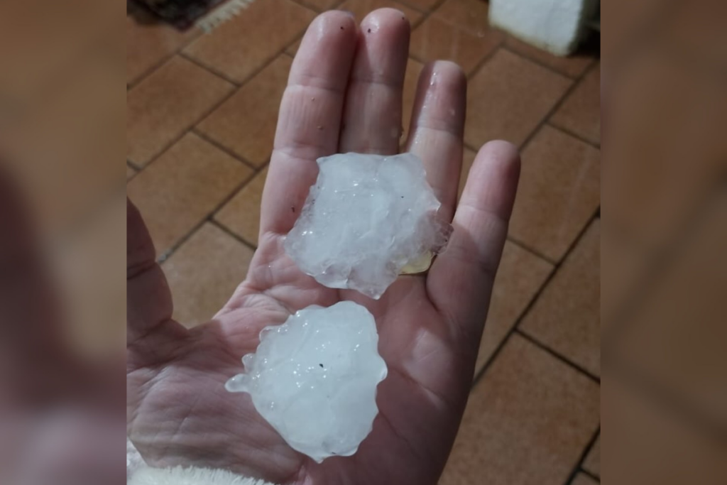 Mão segurando pedra de gelo (granizo) grandes