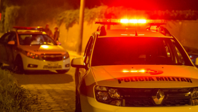 Duas viaturas da Polícia Militar com luzes ligadas
