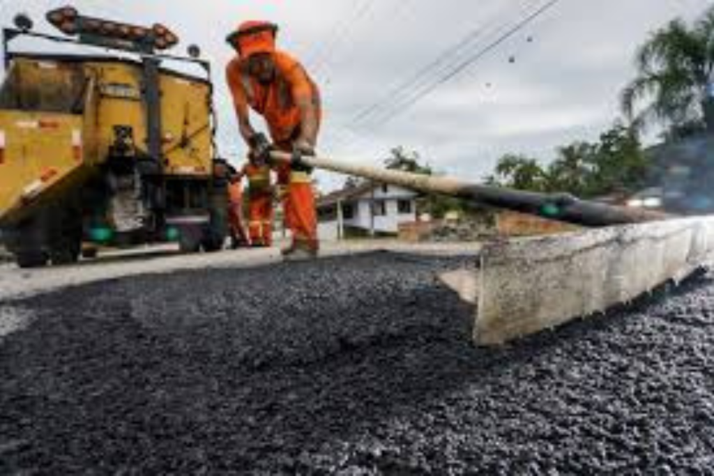 Maquinário e trabalhador pavimentando rodovia