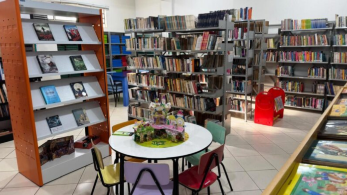 Sala com prateleiras cheias de livros em uma biblioteca pública.