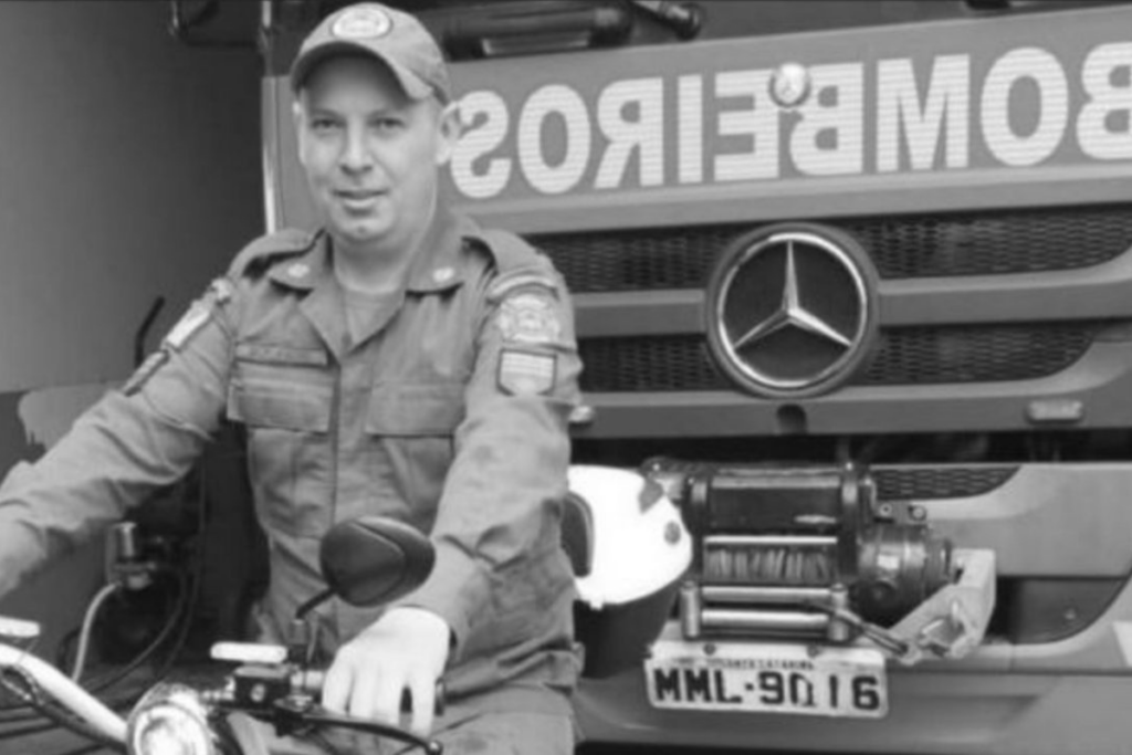 Andrei Marcos Rodrigues, bombeiro morto a facadas em Palma Sola sentado em uma moto a frente de um caminhão Mercedes