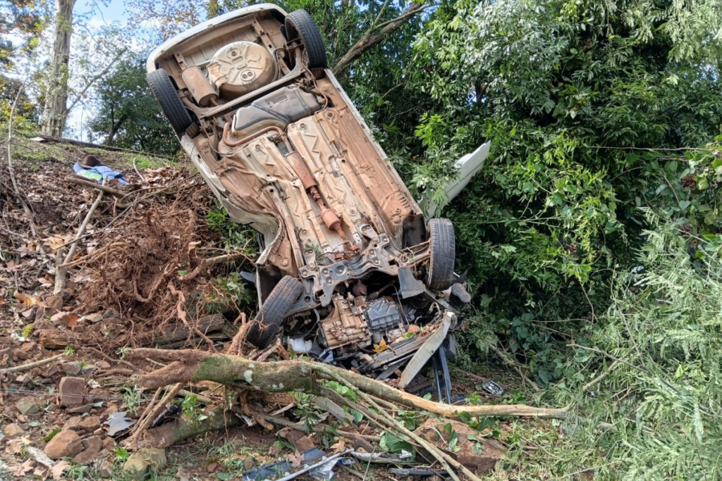 Veículo com as rodas para cima em uma ribanceira e pendurado em uma árvore