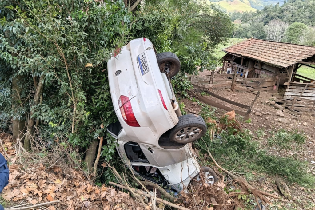 Veículo com as rodas para cima em uma ribanceira e pendurado em uma árvore