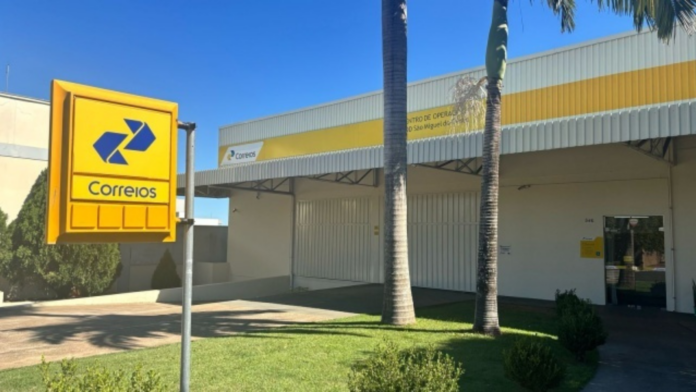 Fachada de uma agência dos Correios com placa amarela na frente