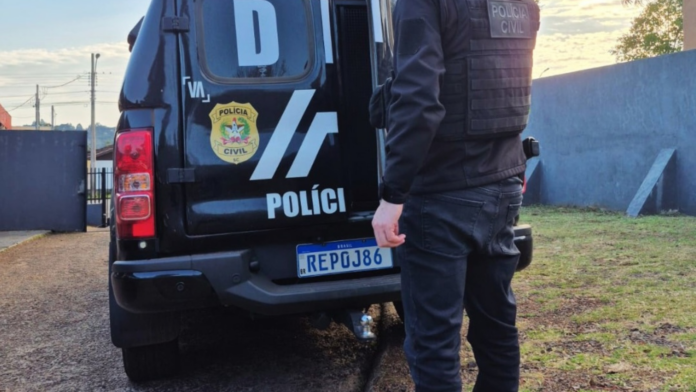 Veículo da Polícia Civil e agente em rua de terra com gramado ao lado.