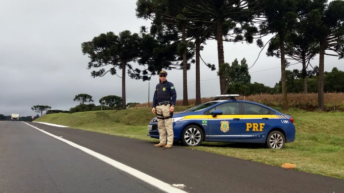 Rodovia com veículo e agente da PF na lateral