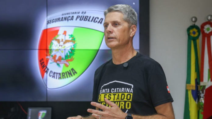 Segundo o secretário de Estado da Segurança Pública, coronel Flávio Graff á frente de um telão com a logo daSegurança Pública