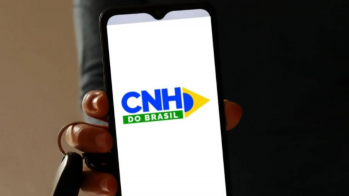Mão segurando a chave de um carro e um celular com o App CNH Brasil aberto